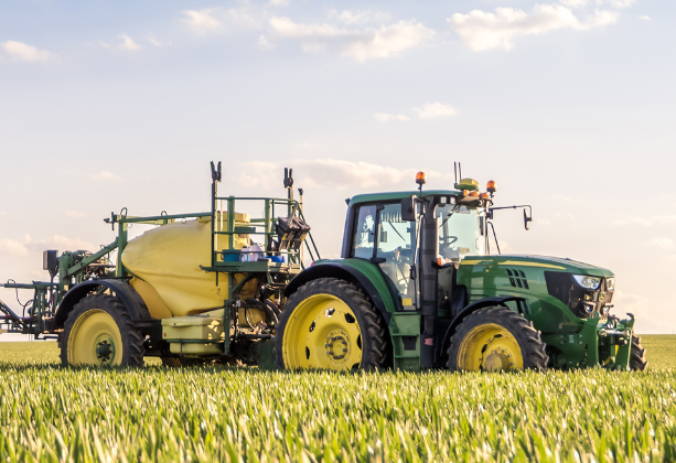 Image of a tractor in the field with spraying equipment, ready to spray